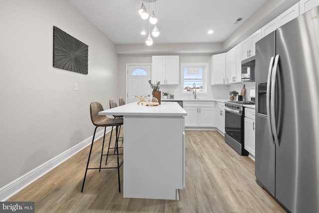 kitchen featuring white cabinetry, stainless steel appliances, a center island, and a kitchen bar