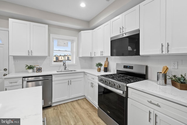 kitchen with sink, backsplash, stainless steel appliances, and white cabinets