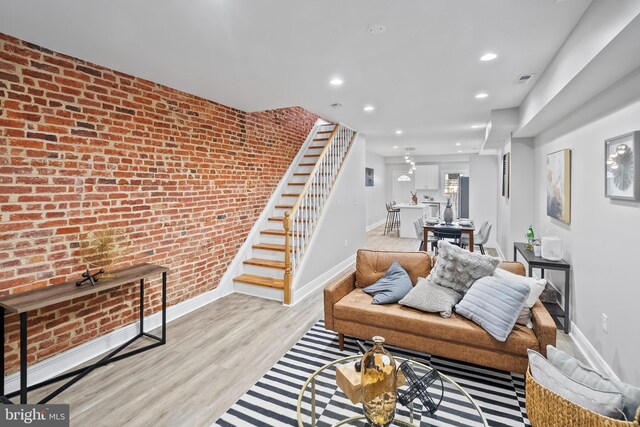 living room featuring brick wall and light hardwood / wood-style floors