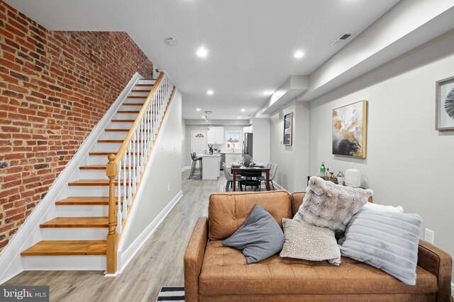 living room with brick wall and light wood-type flooring