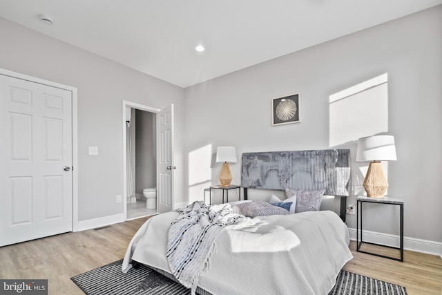 bedroom with ensuite bath and light hardwood / wood-style flooring