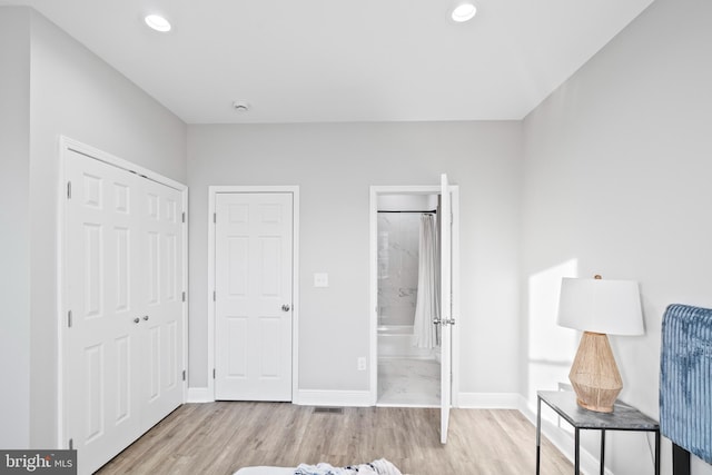 unfurnished bedroom featuring ensuite bath and light hardwood / wood-style flooring