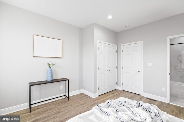 bedroom with ensuite bath and wood-type flooring