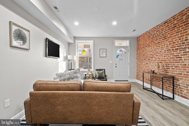 living room with brick wall and light hardwood / wood-style floors