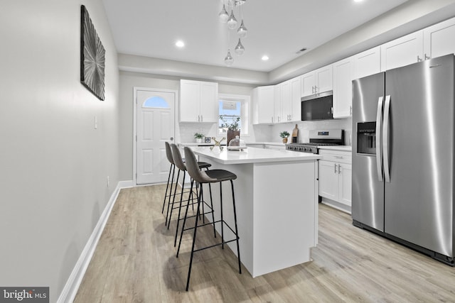 kitchen with stainless steel refrigerator with ice dispenser, tasteful backsplash, stove, a kitchen island with sink, and white cabinets