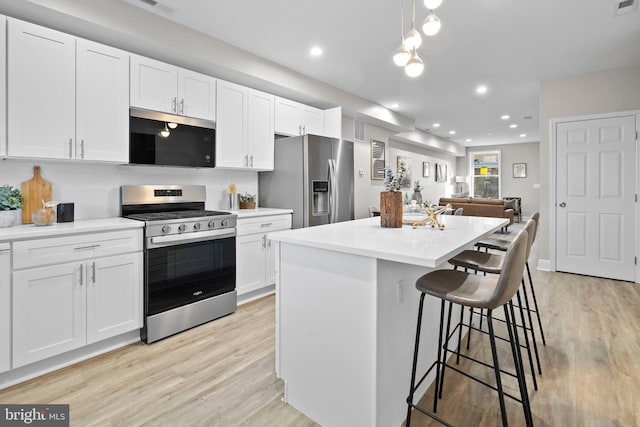 kitchen with stainless steel appliances, a center island, pendant lighting, and white cabinets