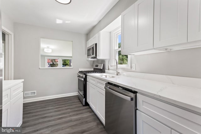 kitchen featuring stainless steel appliances, white cabinetry, light stone countertops, and sink