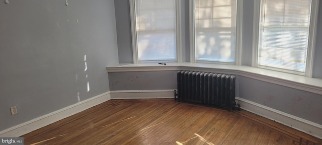 unfurnished room featuring radiator heating unit and wood-type flooring