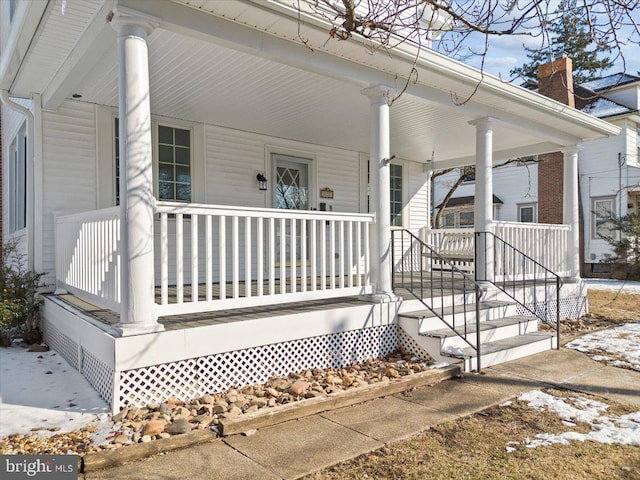 snow covered property entrance with covered porch