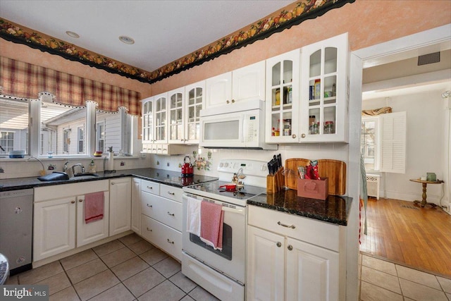 kitchen featuring light tile patterned floors, white appliances, sink, white cabinetry, and radiator heating unit