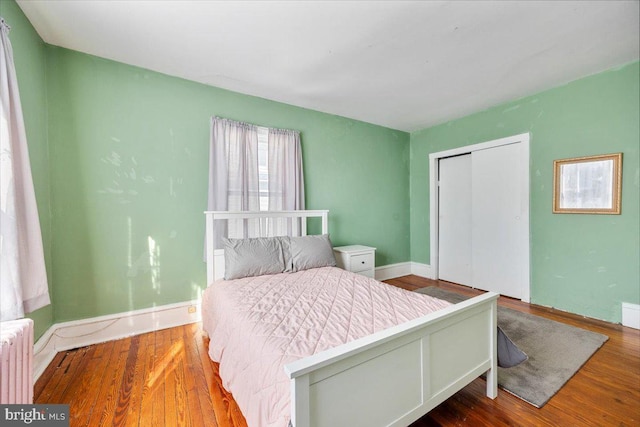 bedroom with hardwood / wood-style floors, radiator heating unit, and a closet