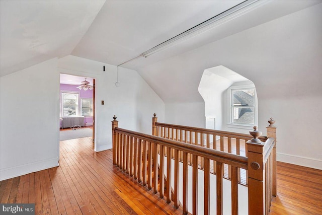 hall featuring lofted ceiling, hardwood / wood-style floors, and radiator heating unit