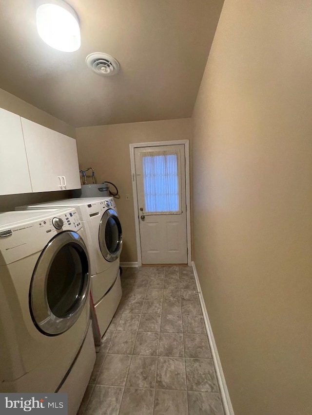 clothes washing area featuring washing machine and dryer, cabinets, and light tile patterned floors