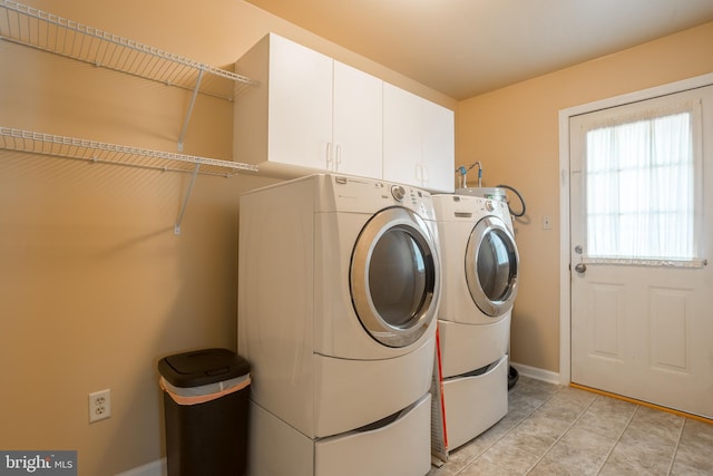 laundry area with independent washer and dryer, cabinets, and light tile patterned flooring