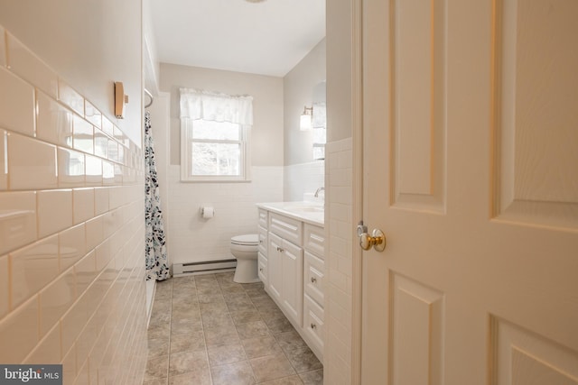 bathroom featuring baseboard heating, tile patterned flooring, tile walls, vanity, and toilet