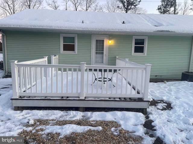 snow covered back of property featuring a deck