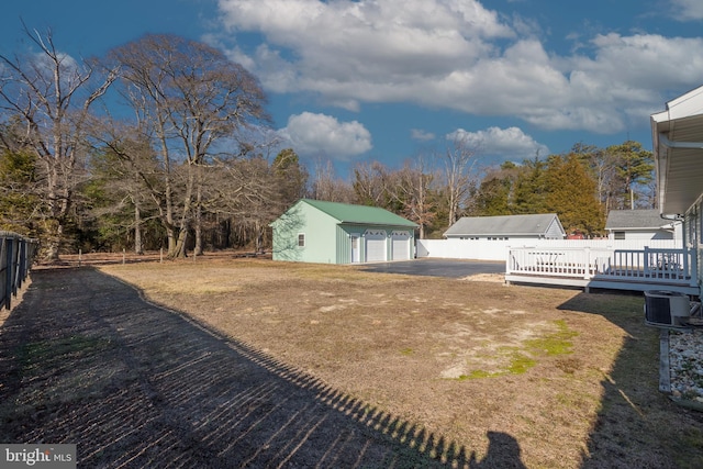 view of yard featuring a wooden deck, a garage, an outdoor structure, and central AC