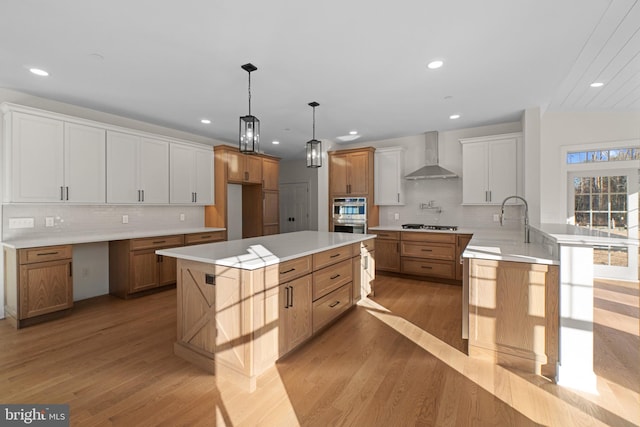 kitchen with light wood-style floors, recessed lighting, wall chimney range hood, and gas stovetop