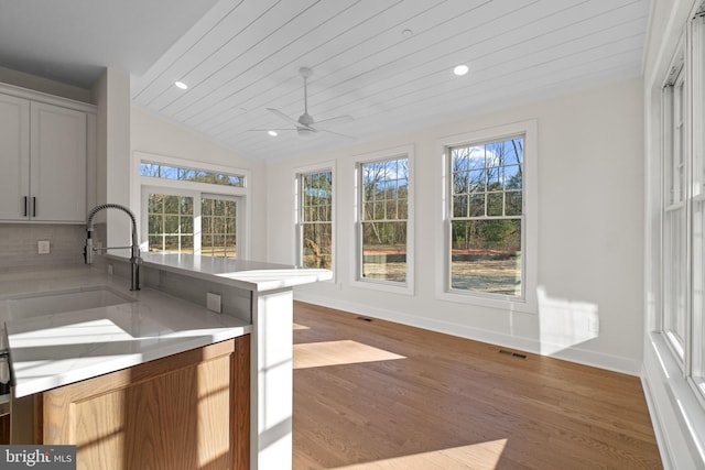 kitchen featuring lofted ceiling, light countertops, visible vents, a sink, and wood finished floors