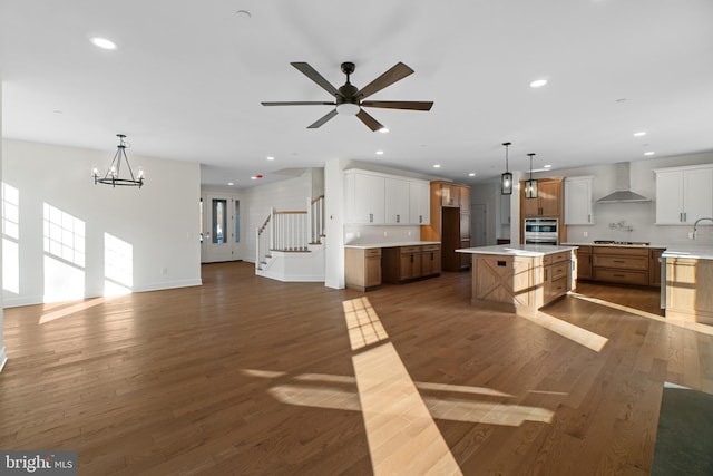 kitchen featuring wall chimney exhaust hood, open floor plan, dark wood finished floors, and recessed lighting