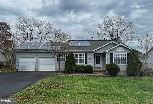 ranch-style home featuring a front lawn, a garage, and solar panels