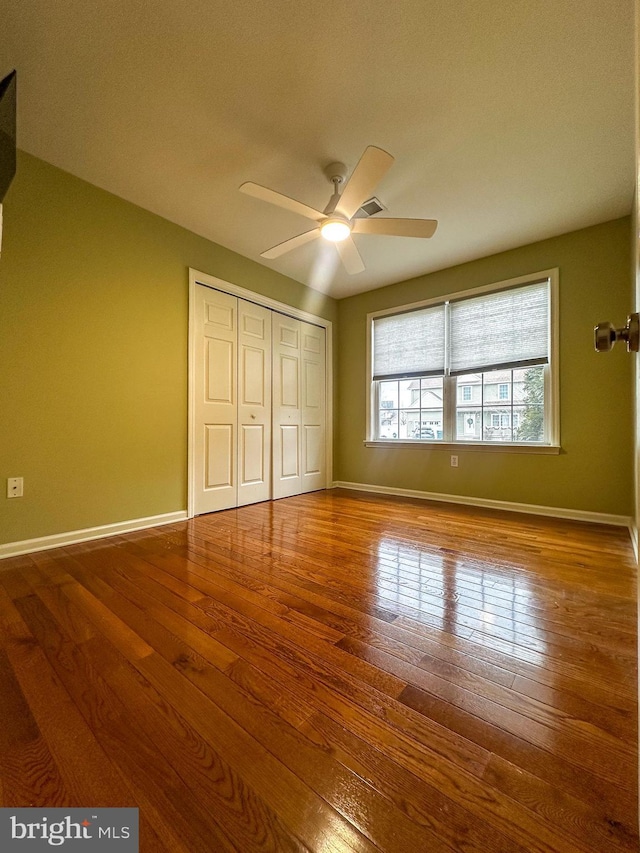 unfurnished bedroom with ceiling fan, a closet, and wood-type flooring