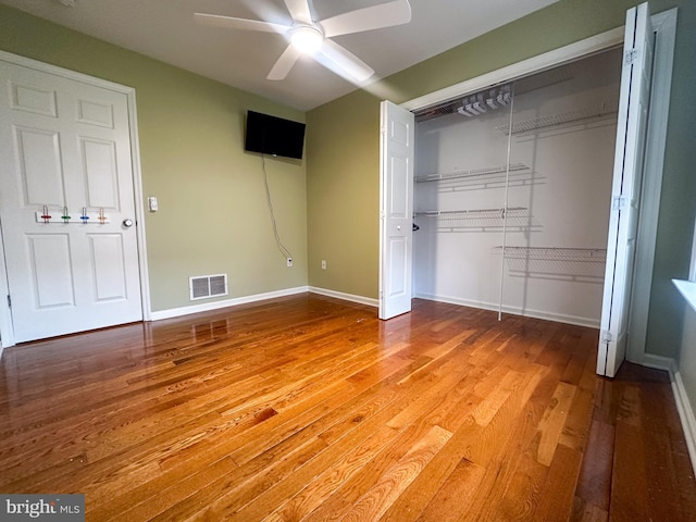 unfurnished bedroom with ceiling fan, a closet, and hardwood / wood-style floors