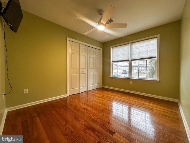 unfurnished bedroom with ceiling fan, hardwood / wood-style flooring, and a closet