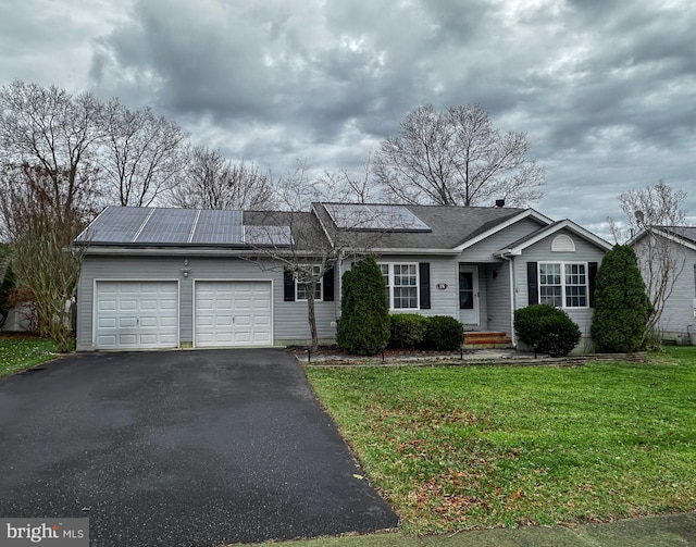 ranch-style home with a front lawn, solar panels, and a garage