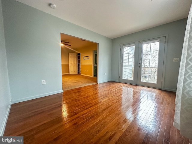 empty room with ceiling fan, french doors, and wood-type flooring