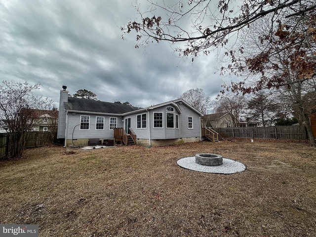 rear view of property featuring an outdoor fire pit and a yard