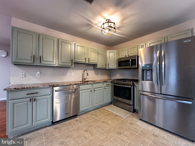 kitchen with sink, appliances with stainless steel finishes, and dark stone counters