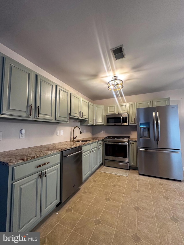 kitchen featuring dark stone counters, appliances with stainless steel finishes, sink, and light tile patterned flooring