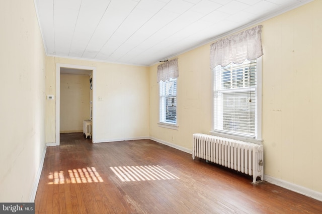 unfurnished room with hardwood / wood-style flooring, radiator heating unit, and crown molding