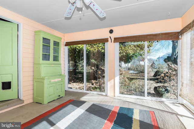 unfurnished sunroom featuring ceiling fan and a wealth of natural light