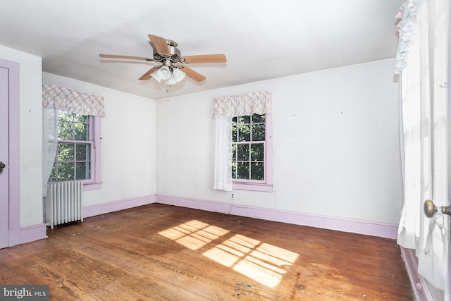 unfurnished room with dark wood-type flooring, radiator heating unit, and ceiling fan