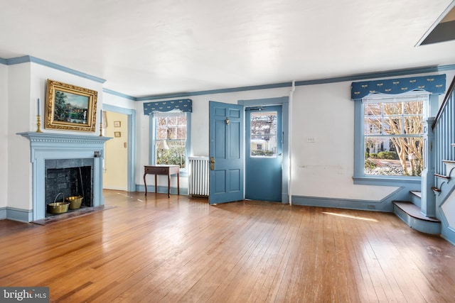 unfurnished living room featuring hardwood / wood-style flooring and crown molding