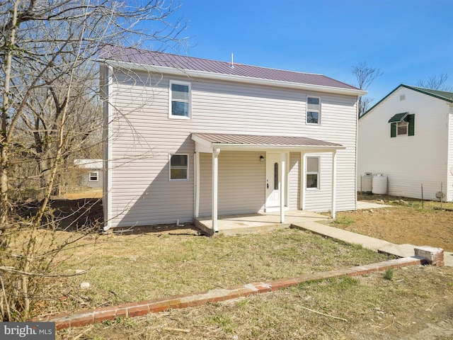 back of house with a patio, a lawn, and metal roof