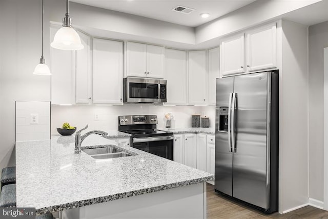 kitchen featuring kitchen peninsula, stainless steel appliances, hanging light fixtures, white cabinets, and sink