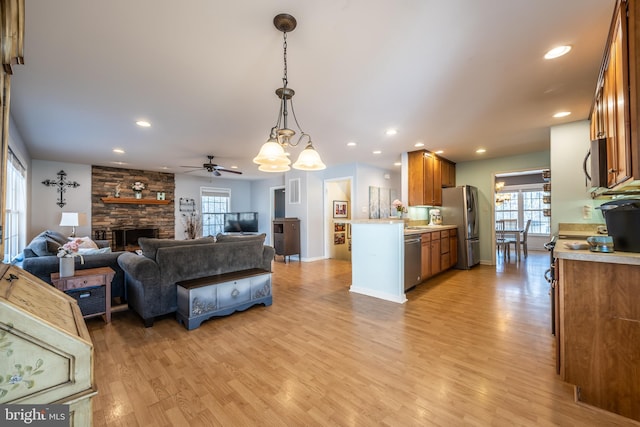 living room featuring a fireplace, light hardwood / wood-style floors, and ceiling fan