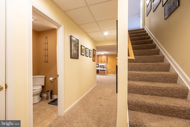 stairs featuring tile patterned flooring and a paneled ceiling