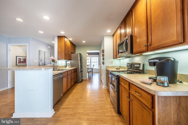 kitchen with sink, light hardwood / wood-style flooring, stainless steel appliances, and a kitchen bar