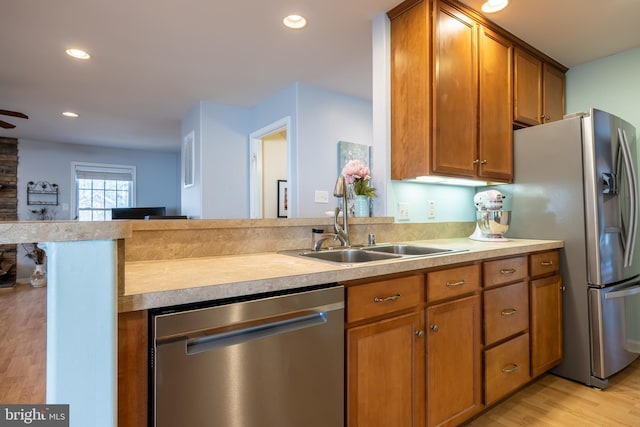 kitchen with sink, light wood-type flooring, kitchen peninsula, ceiling fan, and stainless steel appliances