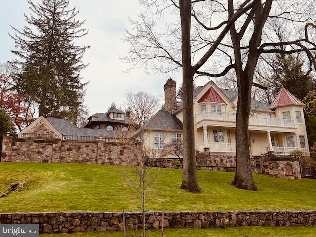 rear view of property featuring a balcony and a yard