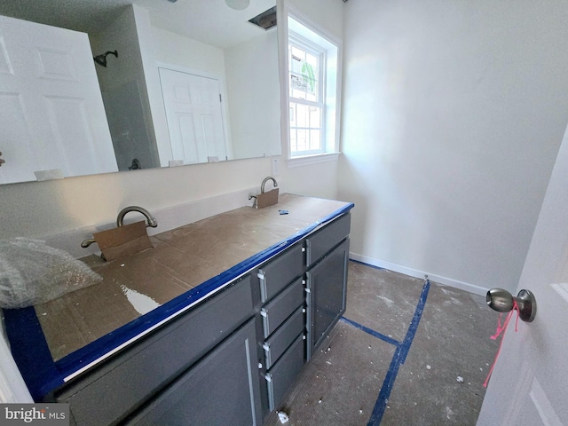 bathroom with a sink, baseboards, a shower, and double vanity