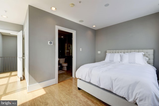 bedroom with ensuite bath and light hardwood / wood-style floors