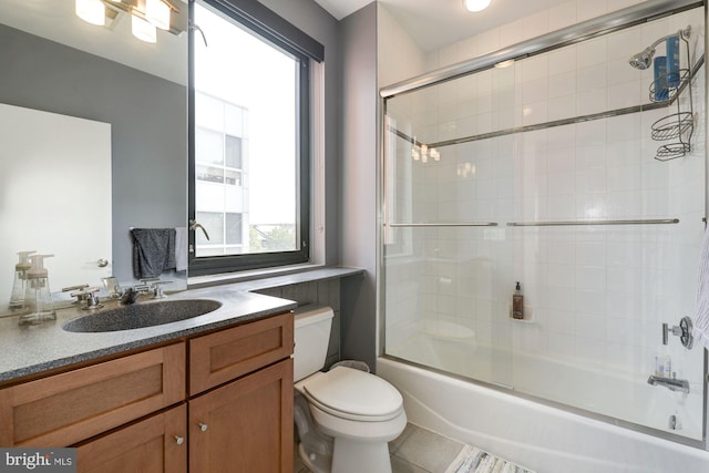 full bathroom with tile patterned flooring, vanity, combined bath / shower with glass door, and toilet