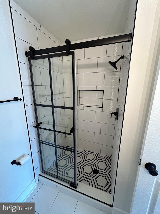 bathroom with an enclosed shower and tile patterned flooring