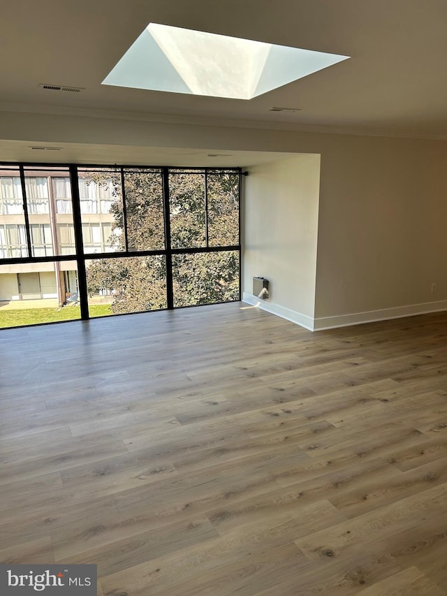 spare room with a skylight, ornamental molding, and hardwood / wood-style floors