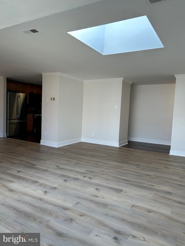 unfurnished living room with light hardwood / wood-style floors, crown molding, and a skylight